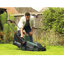 Un homme utilise une tondeuse à gazon dans le jardin.