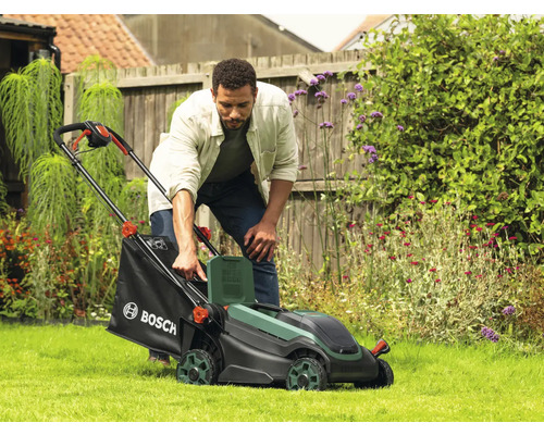 Un homme utilise une tondeuse à gazon dans le jardin.