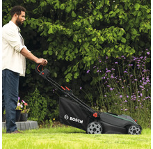 Un homme utilise une tondeuse à gazon dans le jardin. Logo Bosch.