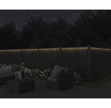 Abendliche Gartenszene mit beleuchtetem Holzzaun und Gartenmöbeln