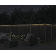 Gartenmöbel auf Terrasse mit beleuchtetem Zaun bei Nacht