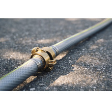 Tuyau d'arrosage avec raccord en laiton sur asphalte