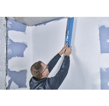 Un homme lisse un mur avec une lisseuse de Knauf