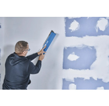 Un homme lisse un mur avec une spatule à lisser Knauf