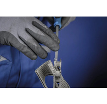 Une personne travaille une pièce à l'aide d'une lime tout en portant des gants de protection.