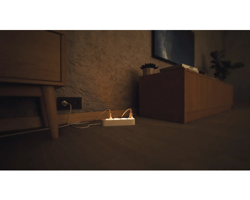 Mehrfachsteckdose mit eingesteckten Stromkabeln in einem Wohnzimmer.