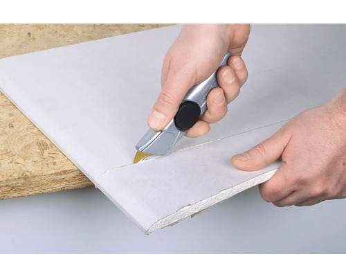 Zuschneiden einer Gipskartonplatte mit einem Cutter.