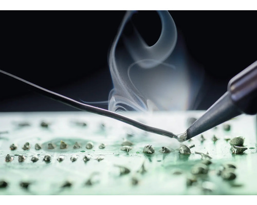 Lötkolben beim Löten auf einer Platine mit Rauch