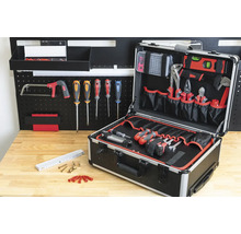 Offener Werkzeugkoffer mit Werkzeugen und Zubehör vor Werkbank und Werkzeugwand