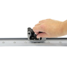 Une main installe un guide de porte coulissante sur un rail