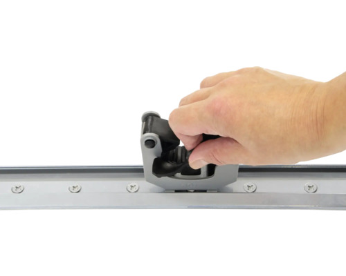 Une main installe un guide de porte coulissante sur un rail