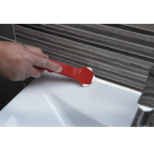 Une personne utilise un outil de lissage des joints pour lisser un joint sur un lavabo.