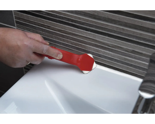 Une personne utilise un outil de lissage des joints pour lisser un joint sur un lavabo.