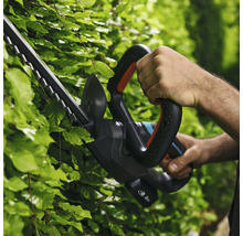 Une personne utilise un taille-haie pour tailler une haie