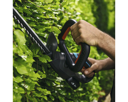 Une personne utilise un taille-haie pour tailler une haie