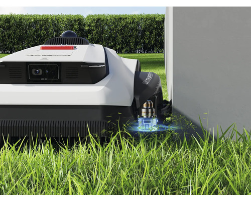 Robot tondeuse sur gazon près d'un mur