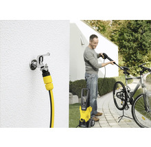 Un homme nettoie un vélo avec un nettoyeur haute pression Kärcher. On peut également voir un robinet avec un raccord de tuyau.