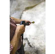 Eine Person benutzt einen Hochdruckreiniger zur Reinigung einer Oberfläche.