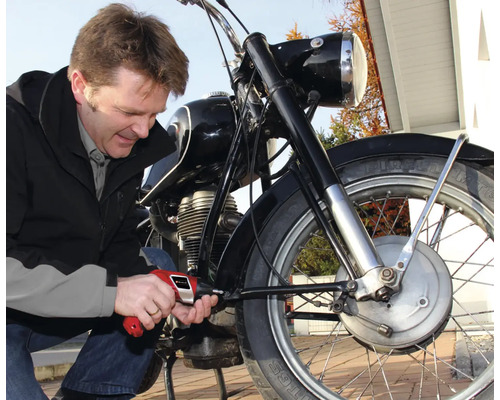 Mann repariert Motorrad mit Schraubendreher