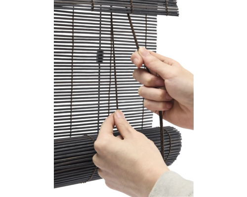 Person bedient eine Bambus Jalousie mit Zugschnur.