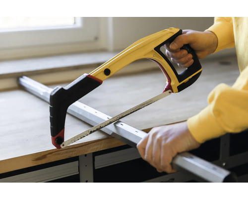 Mann sägt Metallprofil mit einer Bügelsäge