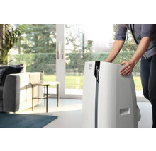 Une femme place un climatiseur mobile DeLonghi dans le salon.