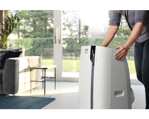 Une femme place un climatiseur mobile DeLonghi dans le salon.
