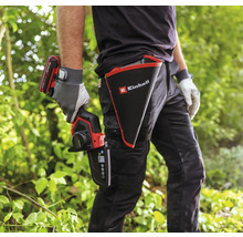 Une personne avec une scie à branches sans fil Einhell et un étui avec le logo Einhell