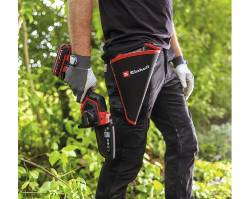 Une personne avec une scie à branches sans fil Einhell et un étui avec le logo Einhell