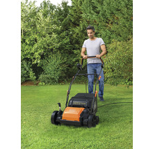 Ein Mann mäht Rasen mit einem Rasenmäher der Marke Black and Decker in einem Garten.