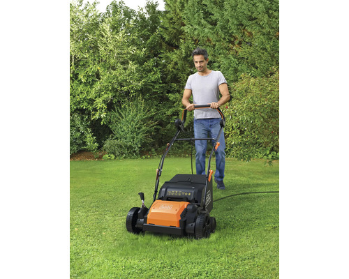 Ein Mann mäht Rasen mit einem Rasenmäher der Marke Black and Decker in einem Garten.