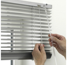 Gros plan d'une personne manipulant un store vénitien pour ajuster la lumière