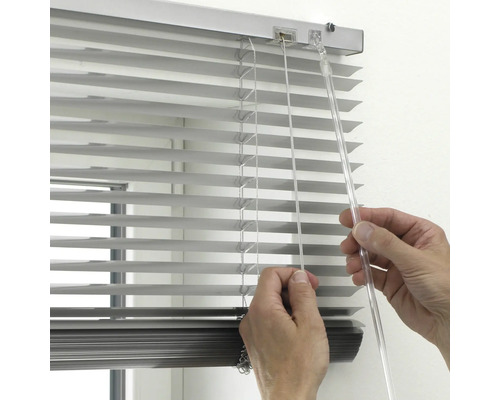 Gros plan d'une personne manipulant un store vénitien pour ajuster la lumière