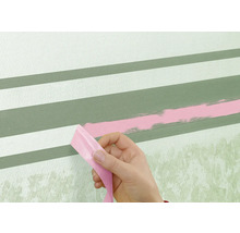 Une personne retire du ruban adhésif d'un mur avec des rayures peintes.