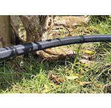 Tuyau d'arrosage dans le jardin avec de l'eau qui s'échappe