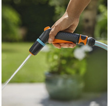 Une main tient un pulvérisateur de jardin d'où sort de l'eau.