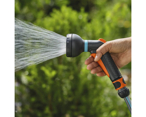 Eine Hand hält eine Gartenspritze, aus der Wasser austritt.