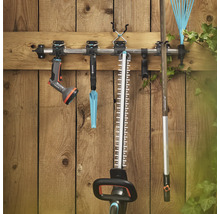 Outils de jardin tels qu'un taille-haie, un râteau à gazon et un pulvérisateur de jardin sur un support à outils sur un mur en bois