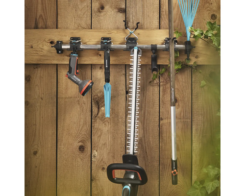 Outils de jardin tels qu'un taille-haie, un râteau à gazon et un pulvérisateur de jardin sur un support à outils sur un mur en bois