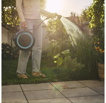 Femme arrosant des plantes avec un enrouleur de tuyau dans le jardin.