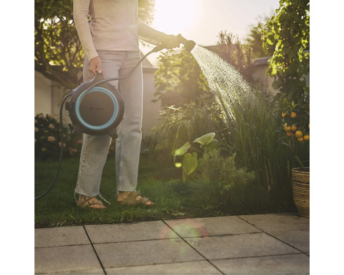 Femme arrosant des plantes avec un enrouleur de tuyau dans le jardin.