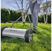 Tondeuse à gazon manuelle avec une personne dans le jardin.