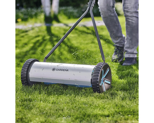 Tondeuse à gazon manuelle en fonctionnement sur une pelouse avec le logo Gardena