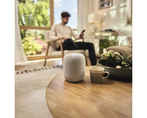 Haut-parleur intelligent sur une table ronde en bois dans un salon