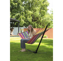 Femme assise dans un hamac rayé avec cadre dans le jardin.