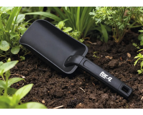 Gartenschaufel im Beet mit for_q Logo auf dem Griff