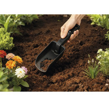 Gartenschaufel in der Erde mit Blumen im Hintergrund