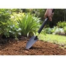 Une personne utilise une pelle de jardin dans un parterre.