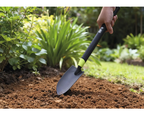 Une personne utilise une pelle de jardin dans un parterre.