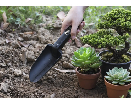 Pelle de jardin avec marquages en cours d'utilisation à côté de plantes en pot.